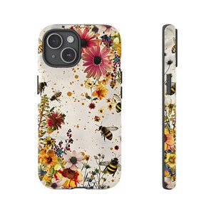 May include: A white iPhone case with a floral pattern featuring bees and yellow, red, and orange flowers. The case has a clear background with a subtle speckled pattern.