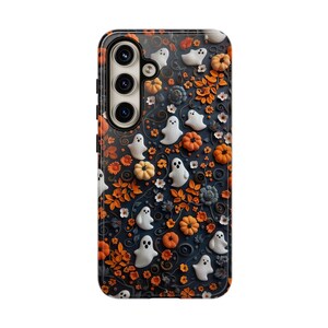 May include: A phone case with a Halloween theme. The case features a dark blue background with white ghosts, orange pumpkins, and orange leaves. The case has a glossy finish and a camera cutout.