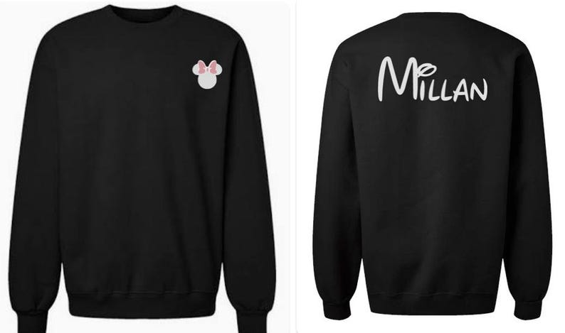 May include: A black long-sleeve sweatshirt featuring a small white mouse head icon with a pink bow on the front left chest and the white text "Millan" in a cursive script font printed across the upper back area of the garment.