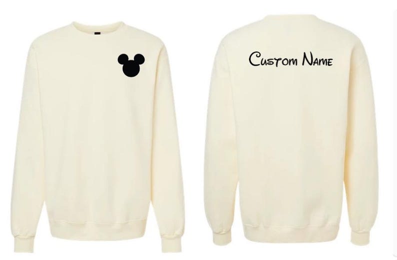 May include: A cream-colored long-sleeve crewneck sweatshirt. The front features a small black silhouette of a mouse head on the left chest. The back displays the text Custom Name in a black script font centered near the top of the garment.