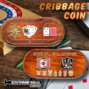 May include: A wooden cribbage coin with a compass rose, playing cards, and the text "CRIBBAGE COIN." The coin's reverse side features a playing card, military insignia, and the text "STAND BY... STILL COUNTING."