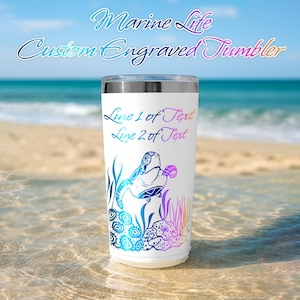 May include: White custom engraved tumbler with a marine life design. The tumbler features a sea turtle and coral in blue, purple, and teal. The text "Marine Life Custom Engraved Tumbler" is at the top, and "Line 1 of Text" and "Line 2 of Text" are written on the tumbler.