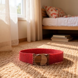 Pode incluir: Um cinto vermelho com contas e uma fivela de madeira com um design circular. O cinto est&aacute; sobre um tapete tecido. A fivela tem um padr&atilde;o de gr&atilde;o de madeira escura. O cinto tem cerca de 7.6 cm de largura.