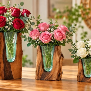May include: Three natural wood log vases of varying heights, each featuring a clear glass insert. The tallest holds red roses, the medium holds pink roses, and the shortest holds white roses, all accented with green eucalyptus and baby's breath.