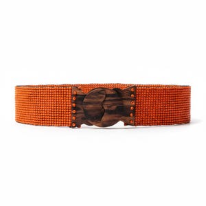 Pode incluir: Um cinto de contas laranja com fivela de madeira. O cinto &eacute; feito de pequenas contas redondas e apresenta uma fivela de madeira escura com um design curvo &uacute;nico. O cinto tem aproximadamente 5 cm de largura.