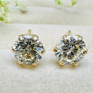 May include: A pair of gold stud earrings with round, clear gemstones.