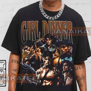 May include: Black t-shirt with the text "GIRL DINNER" in a brown and gold font. The shirt features a collage of male figures in various poses. The overall design has a vintage aesthetic.