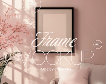 May include: A black picture frame mockup with a white mat and a blank canvas. The frame is hanging on a light pink wall with a couch and a plant in the foreground. The text "Frame Mockup" is written in white on the wall.