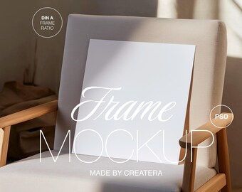 Könnte beinhalten: Ein weißer Rahmen-Mockup auf einem hellbeigen Sessel mit Holzarmlehnen. Der Rahmen liegt auf der Sitzfläche des Sessels. Der Text "Frame Mockup" ist in weißer kursivschrift unter dem Rahmen geschrieben. Der Text "Made by Createra" ist in weißer Schrift unter der Kursivschrift geschrieben. Der Text "DIN A FRAME RATIO" ist in weißer Schrift auf einem weißen Kreis in der oberen linken Ecke des Bildes geschrieben.