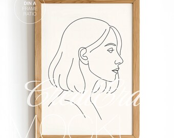 Può includere: Una stampa artistica incorniciata con un disegno a tratto minimalista del profilo di una donna. L'opera è realizzata con linee nere su sfondo color crema. La cornice è in legno chiaro. Il testo "DIN A FRAME RATIO" si trova nell'angolo in alto a sinistra.