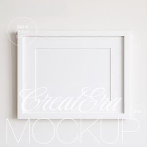 Puede incluir: Un marco de fotos rectangular blanco con un paspartú blanco. El marco tiene un diseño limpio y moderno. El texto "DIN A FRAME RATIO" está en un círculo en la esquina superior izquierda. La palabra "CreateEra" está escrita en cursiva en el centro. La palabra "MOCKUP" está abajo.