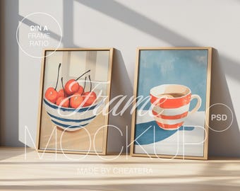 May include: Two framed illustrations, one with a bowl of red cherries and the other with a red and white striped mug. Both frames are made of natural wood and have a light brown finish.