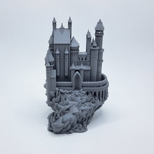 Könnte beinhalten: Ein graues 3D-gedrucktes Modell einer Burg auf einem felsigen Sockel mit Bäumen. Die Burg hat viele Türme und einen großen Bogen-Eingang.