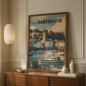 May include: A framed wall art print featuring a scenic illustration of the Dartmouth harbor with boats on the water, a central church tower, and surrounding buildings. The word DARTMOUTH is printed in bold black capital letters at the top.