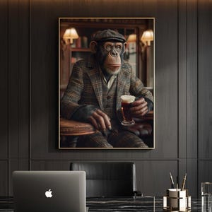 May include: A framed print depicts a chimpanzee in a tweed suit and cap, seated at a table and holding a glass of beer. The artwork has a vintage aesthetic, with warm lighting and a dark background. The print is displayed in a room with a desk and a laptop.