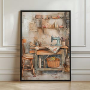 May include: A framed wall art print depicting a sewing workspace with a light blue sewing machine on a wooden table, a wooden chair, a woven basket, and shelves filled with various sewing supplies, spools of thread, and fabric scraps.