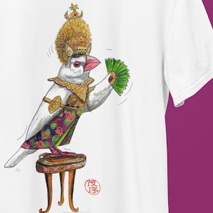 May include: White t-shirt with a detailed illustration of a bird in ornate gold and jewel-toned attire, including a crown and fan. The bird is perched on a small stool, creating a whimsical and artistic design.