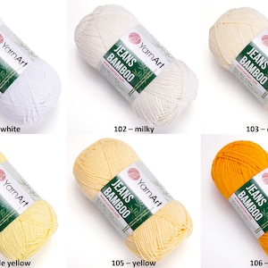 Könnte beinhalten: Sechs Knäuel YarnArt Jeans Bamboo Garn in verschiedenen Farben: Weiß, milchig, Creme, hellgelb, Gelb und Dotter. Das Garn besteht aus Bambus und ist weich und glatt.