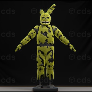 Op de afbeelding: Een groen en zwart animatronisch figuur met een lang, puntig hoofd en een brede grijns. Het figuur heeft een versleten, verweerd uiterlijk, met zichtbare schade aan zijn lichaam en ledematen.