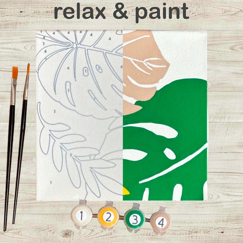 May include: A paint-by-numbers canvas with a tropical leaf design, partially painted in green, beige, and white. The words "relax & paint" are at the top. Includes paintbrushes and numbered paint pots.