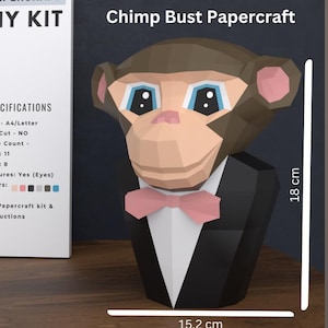 May include: A 3D DIY kit for a Chimp Bust Papercraft. The papercraft chimp is brown, tan, and pink, wearing a black tuxedo with a pink bow tie. The finished papercraft is 18 cm tall and 15.2 cm wide. The kit includes instructions.