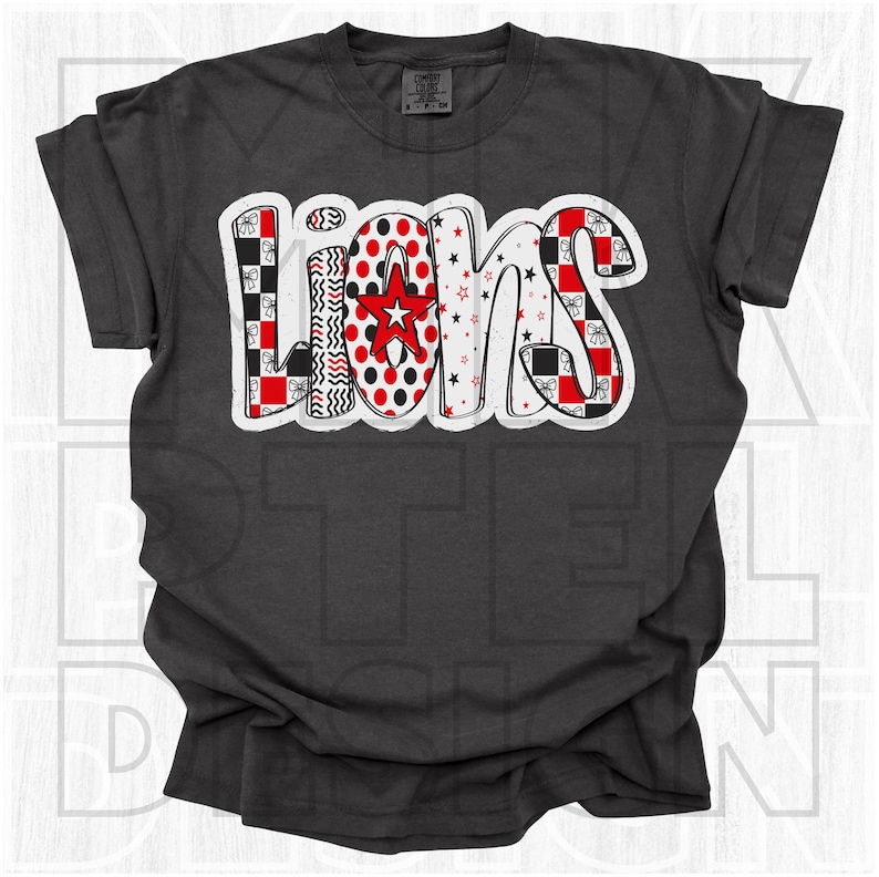 May include: Dark gray t-shirt with the word "LIONS" in a colorful, patterned design. The letters feature red, black, and white patterns, including polka dots, stars, and bows. A red star is in the center of the "O".