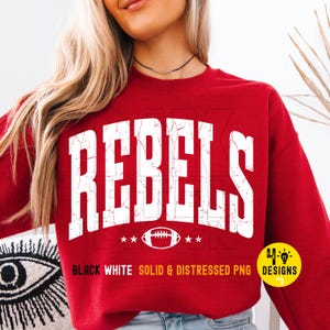 Op de afbeelding: Een rode sweatshirt met het woord "REBELS" in grote, verweerde witte letters. Onder het woord staat een voetbalafbeelding en sterren. De tekst "BLACK WHITE SOLID & DISTRESSED PNG" is ook zichtbaar.