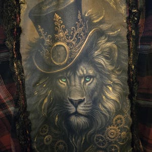 May include: A decorative pillow featuring a lion wearing a top hat with a clock face. The lion has green eyes and gold accents. The pillow is framed with black lace and studs, set against a plaid background.