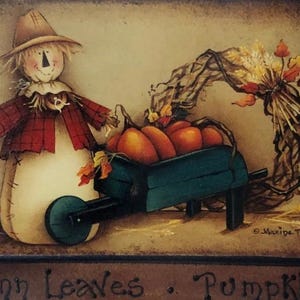 Puede incluir: Pintura con temática otoñal que presenta un espantapájaros, calabazas en una carretilla y una corona decorativa. El espantapájaros lleva una chaqueta a cuadros y un sombrero de paja. La carretilla es verde azulado y las calabazas son naranjas. Las palabras "Autumn Leaves • Pumpkins" están abajo.