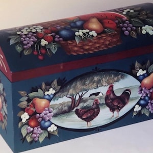 May include: A hand-painted wooden chest with a curved lid, featuring a dark blue base and red accents. The lid displays a basket of fruit, while the front showcases a rural scene with chickens. Decorative fruit clusters adorn the sides.