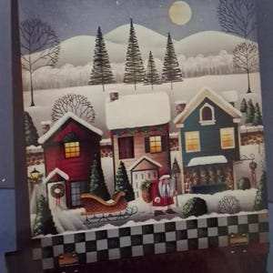 May include: A winter scene with three houses, two of them with lit windows, and a snow-covered landscape. A red sleigh with a white trim is pulled by a reindeer. Santa Claus is walking in the snow with a sack of gifts. The houses are decorated with wreaths and garlands. The sky is a dark blue with a full moon.