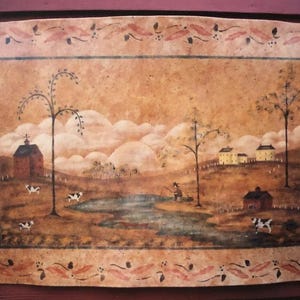 Può includere: Dipinto rustico incorniciato raffigurante un paesaggio rurale. L'opera presenta uno stagno, alberi, case e mucche, il tutto in calde tonalità terrose. Il bordo è ornato da un motivo floreale decorativo, che aggiunge un tocco di eleganza.