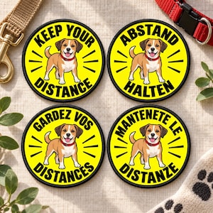 May include: Four circular yellow patches with black borders, each featuring a brown and white dog wearing a red collar. The text reads Keep Your Distance, Abstand Halten, Gardez Vos Distances, and Mantenete Le Distanze in black lettering.