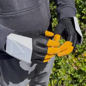 May include: Black and yellow fingerless gloves with white accents. The gloves have a black leather palm and a yellow finger covering. A white, geometric design is on the wrist area.