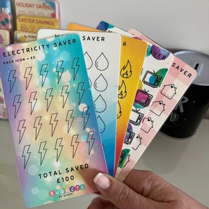 May include: A set of six colorful cards with different icons for tracking savings. The cards are labeled "Electricity Saver", "Water Saver", "Gas Saver", "Food Saver", "Entertainment Saver", and "Other Saver". Each card has a different color and features a unique icon. The cards are designed to help people track their savings and reach their financial goals.
