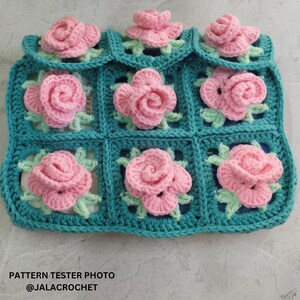 May include: A teal crocheted square with pink crocheted roses in each square. The text "PATTERN TESTER PHOTO @JALACROCHET" is at the bottom of the image.