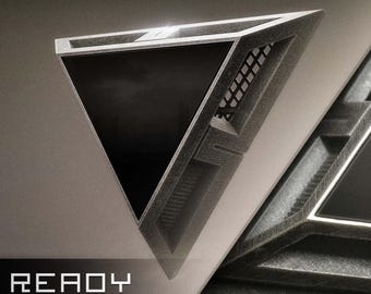 May include: A geometric, triangular object with a dark, reflective surface and a textured, metallic frame. The design features a grid-like pattern and the text "READY TO SHIP" in a modern font. The overall aesthetic is futuristic and industrial.
