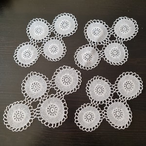 May include: Four white crocheted doilies with a circular design. Each doily is made up of smaller circles connected together.