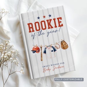May include: A baseball-themed book cover with the text "ROOKIE of the year!" in red and blue. The cover features illustrations of a baseball bat, helmet, jersey, ball, and glove. The text "SWEET WISHES FOR Baby Jackson" is also included.