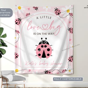 May include: A pink and white baby shower banner with ladybug and daisy graphics. The banner reads "A little love bug is on the way" and "Kate's baby shower". The banner is fully customizable.