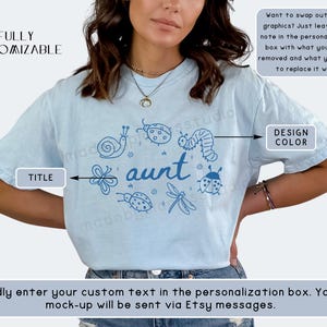 Op de afbeelding: Lichtblauw T-shirt met een blauw insecten- en bloemendesign rond het woord "aunt". Het shirt bevat de tekst "FULLY CUSTOMIZABLE" en instructies om het ontwerp aan te passen. De ontwerpkleur kan worden gewijzigd.