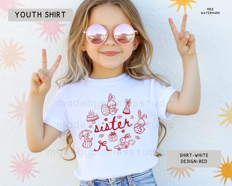 May include: White youth t-shirt with a red graphic design. The design includes the word "sister" and cartoon bunnies, gifts, and a cake. The t-shirt has a crew neck.
