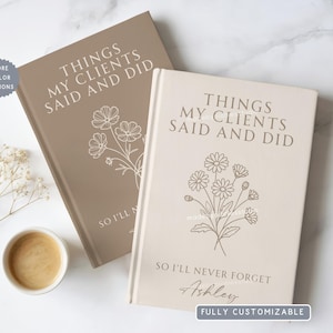 May include: Two hardcover journals with floral illustrations. One is taupe, the other is cream. Text on the covers reads "THINGS MY CLIENTS SAID AND DID" and "SO I'LL NEVER FORGET". The cream journal is personalized with the name "Ashley".