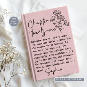 May include: A light pink hardcover book featuring a black line art floral illustration and the text Chapter twenty-one. The cover includes a printed message about celebrating memories and personal growth, finished with the name Sophia in script.