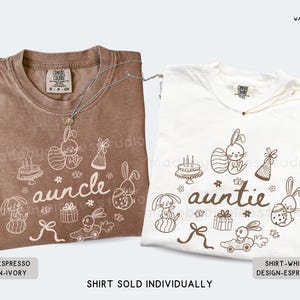 May include: Two t-shirts, one in espresso and one in white, each with a unique design. The espresso shirt says "auncle" and the white shirt says "auntie". Both shirts feature bunny illustrations and the text "SHIRT SOLD INDIVIDUALLY".