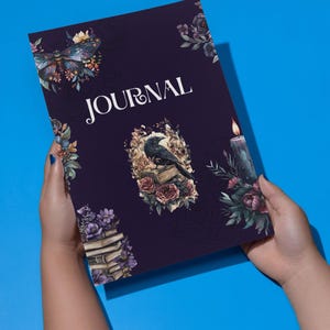 May include: A dark purple journal with the word "JOURNAL" printed in white on the front cover. The cover features a repeating pattern of floral illustrations, including a raven perched on a stack of books, a candle, and a butterfly.
