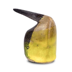 Può includere: Una scultura in ceramica artigianale con un'estensione curva a forma di becco. La scultura presenta una sfumatura di colori, tra cui giallo, marrone e nero. La base è marrone chiaro, che sfuma in giallo e nero nella parte superiore.