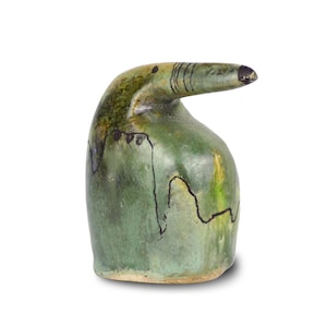Può includere: Una scultura in ceramica verde di un uccello con un lungo becco. L'uccello ha segni neri e una glassa gialla.