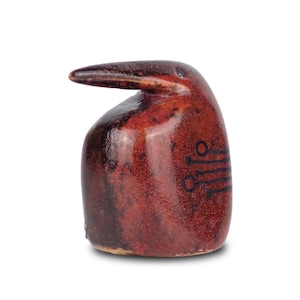 May include: A ceramic bird ornament in red and brown tones. The bird features a long beak and a rounded body. Black markings are on the side. The ornament is likely handmade with a glossy finish. It is a decorative item.