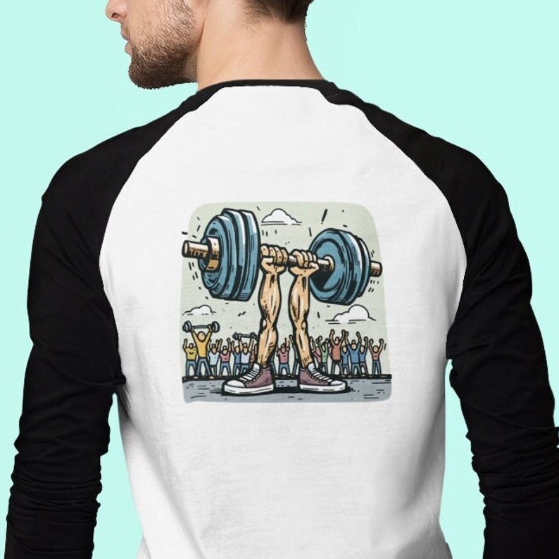 May include: A white and black baseball t-shirt featuring a cartoon illustration of a pair of legs lifting a barbell with a crowd of people cheering in the background.